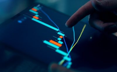 Close-up of a hand pointing at a financial chart on a digital tablet