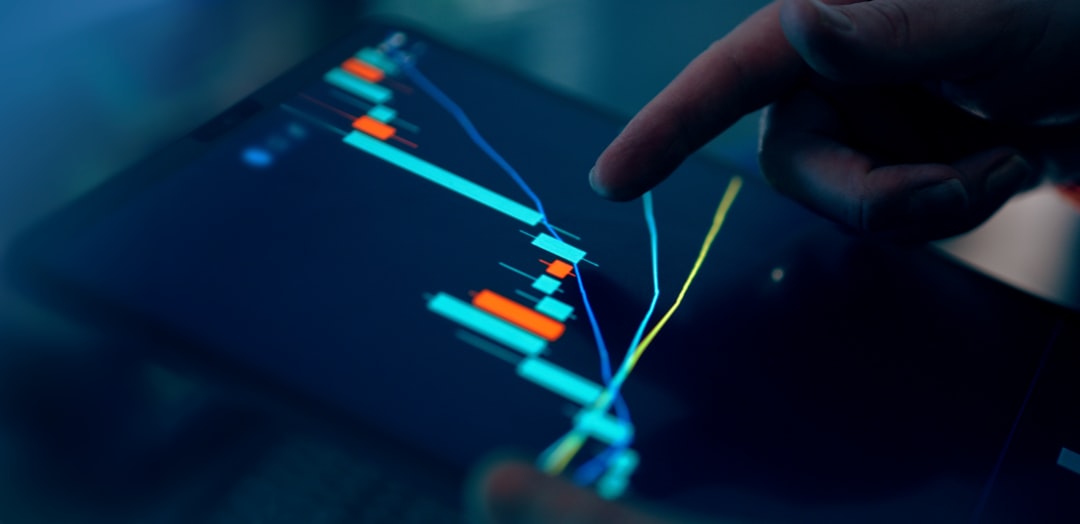 Close-up of a hand pointing at a financial chart on a digital tablet